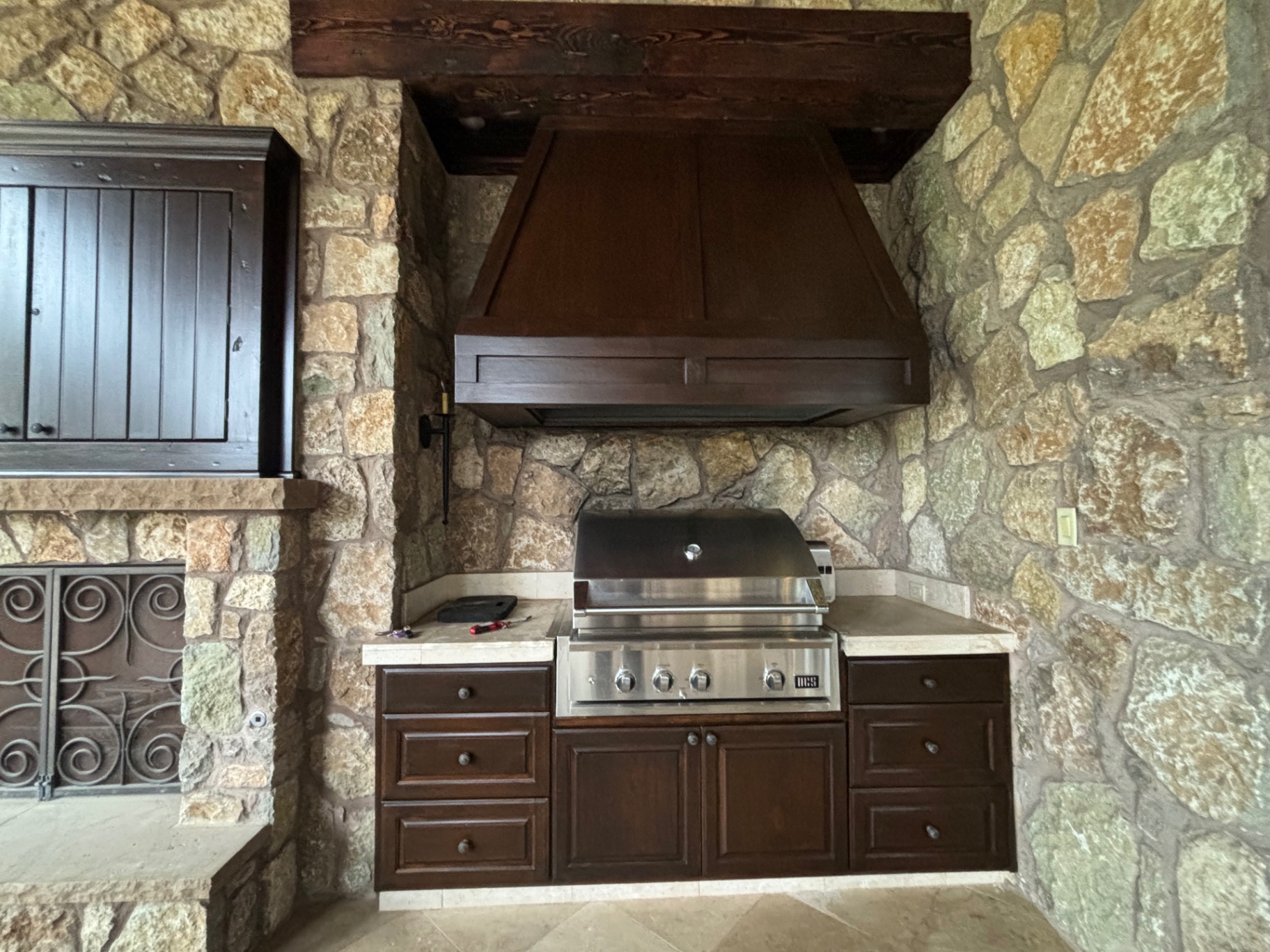 Outdoor kitchen cabinets and vent hood refinished in a deep walnut stain