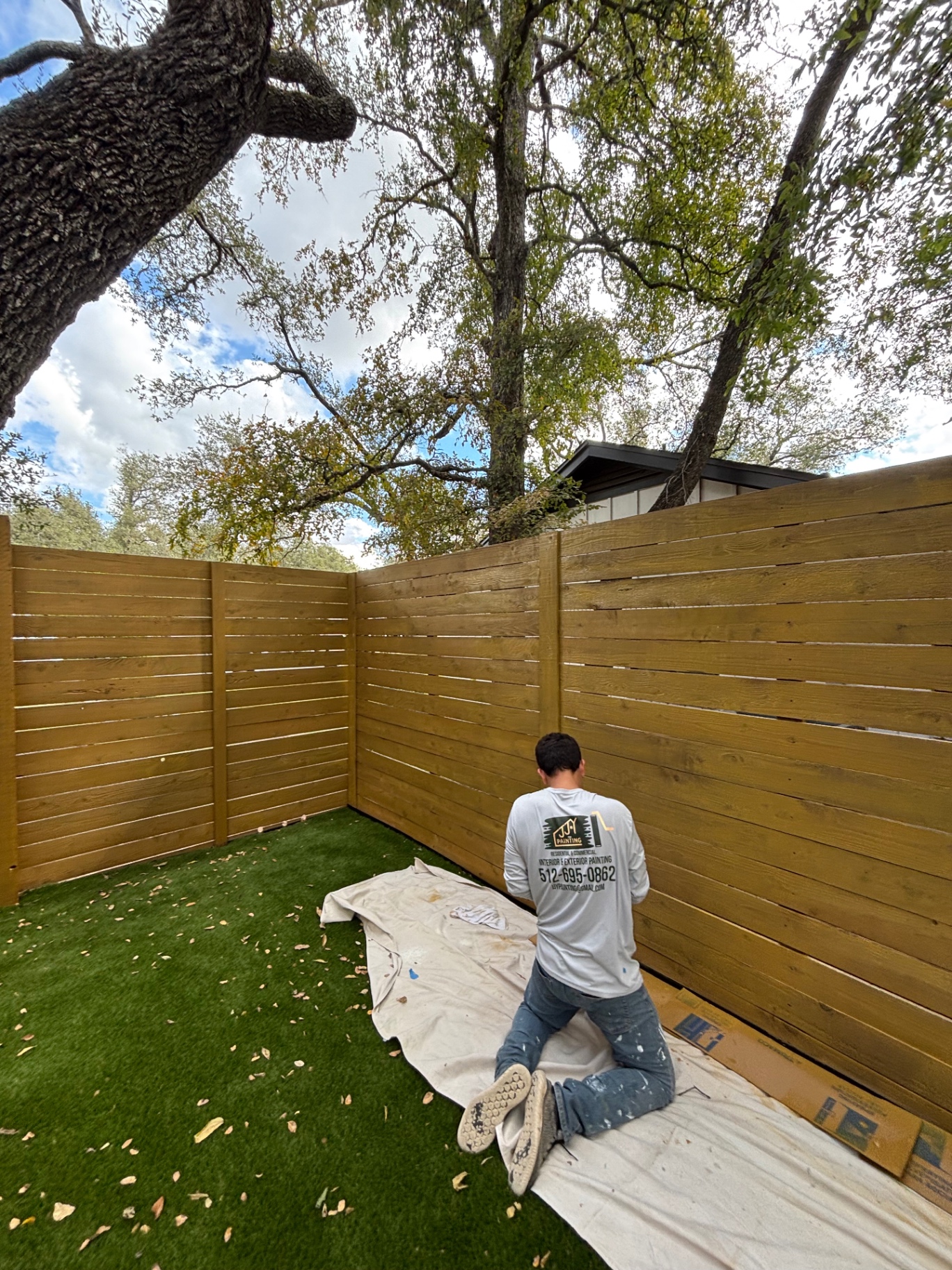 JJY Painting crew member staining a horizontal cedar fence