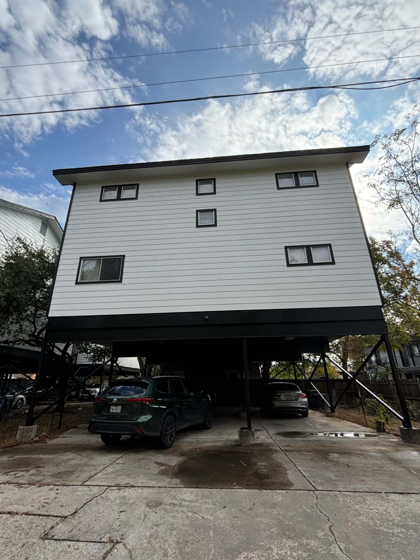 Front view of a raised white home with black trim freshly painted by JJY Painting