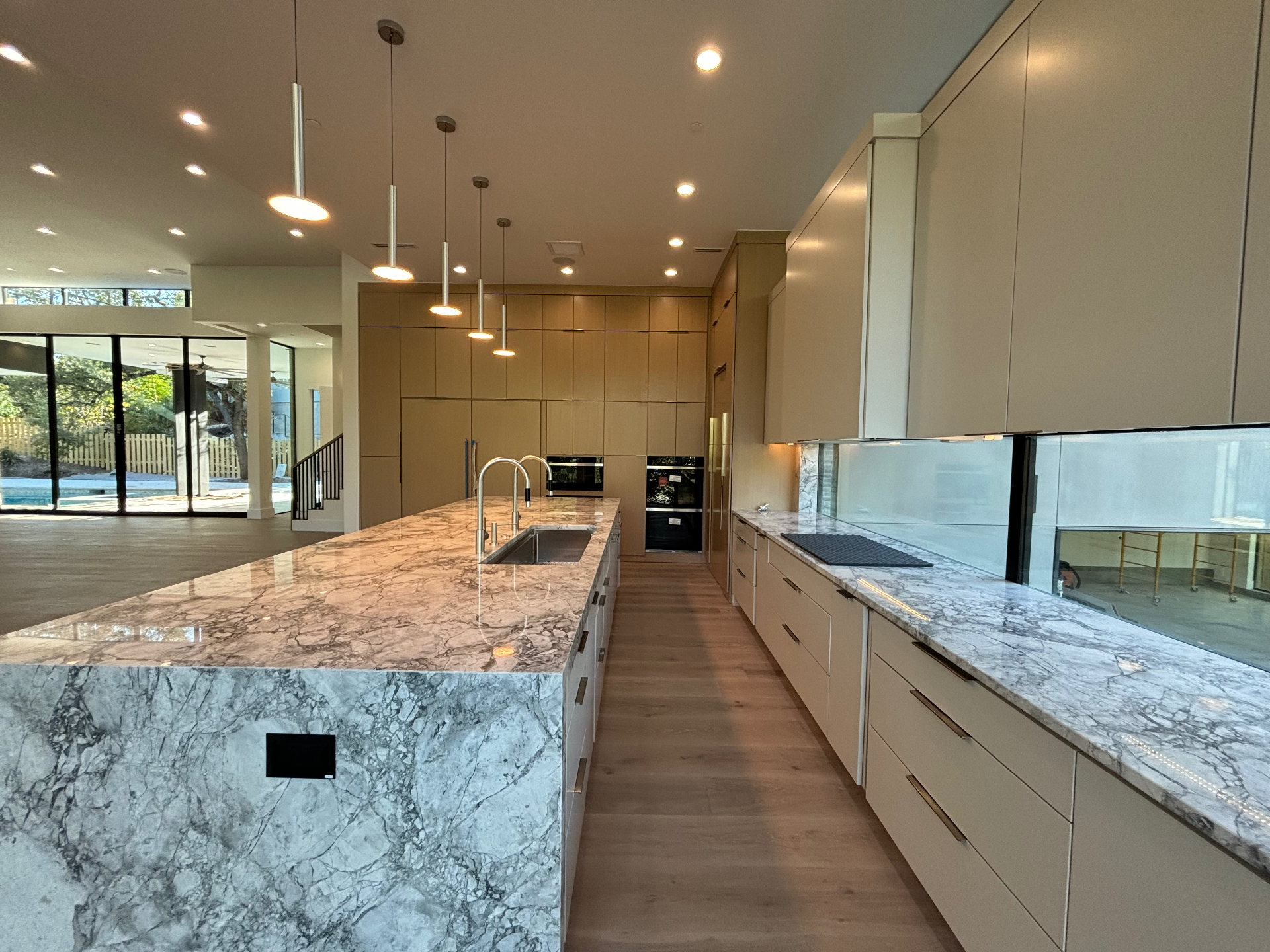 Large kitchen island with a marble waterfall countertop and smooth cream cabinet finish