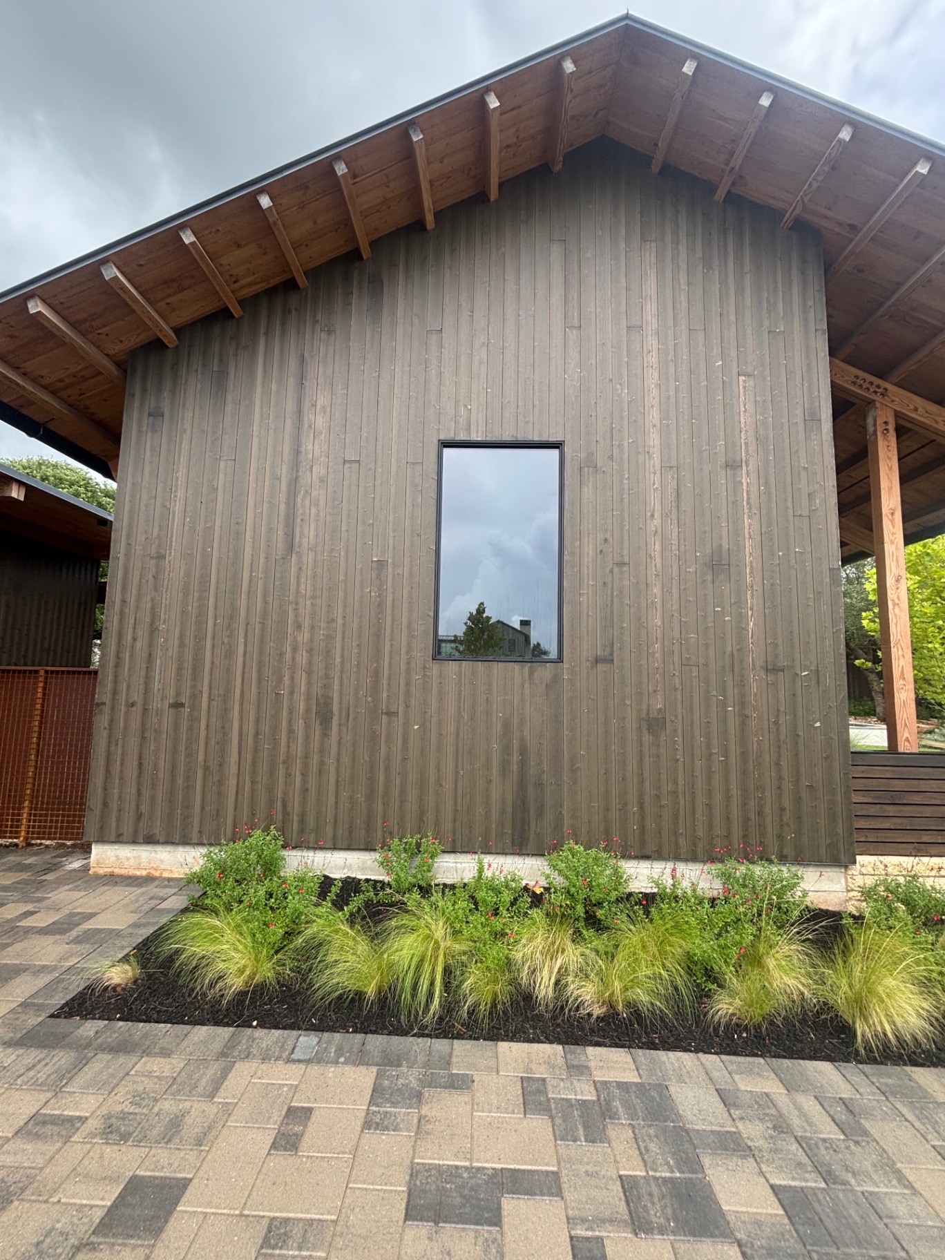 Gable end with dark stained vertical wood siding and timber rafters