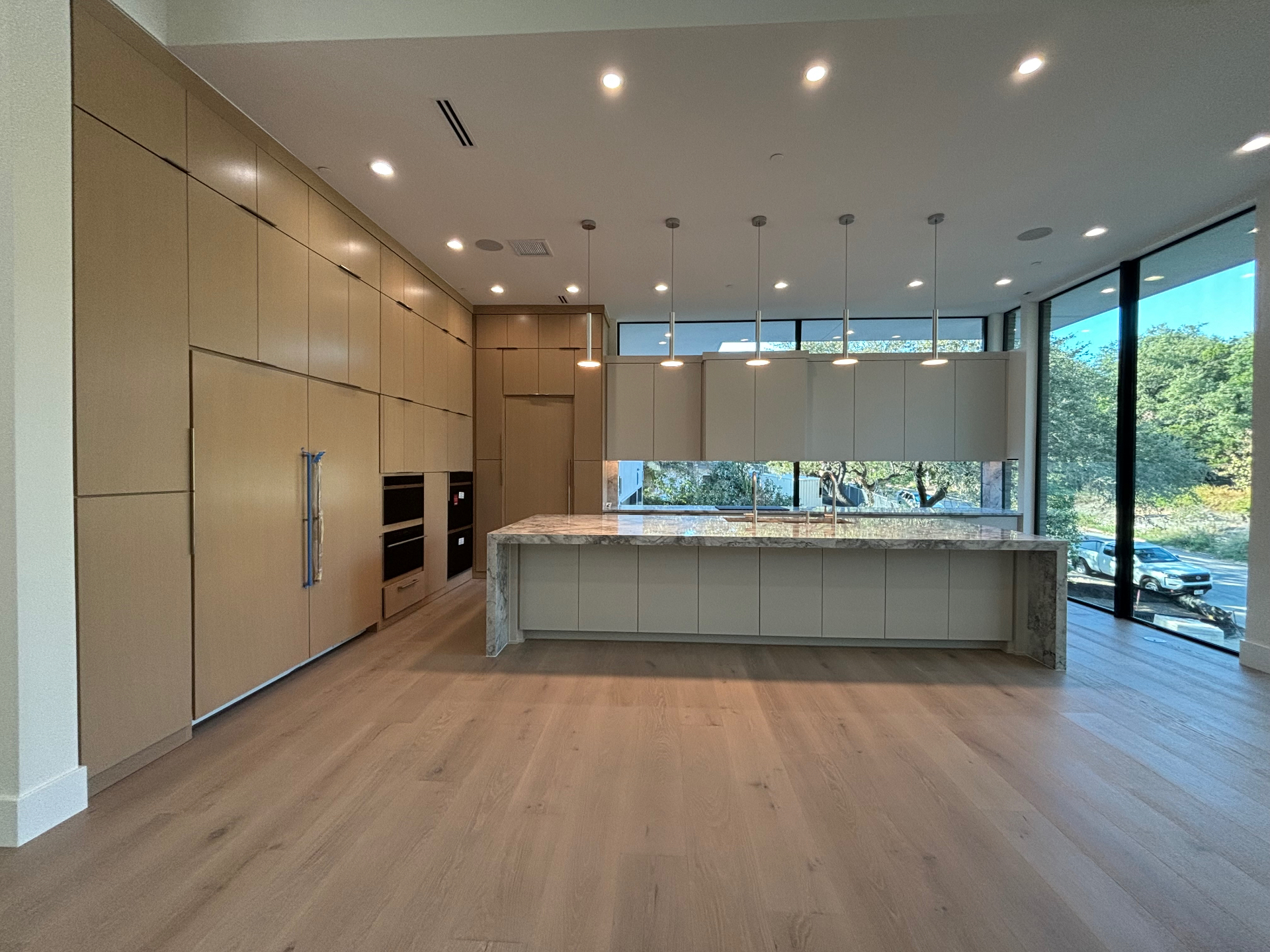 Modern custom home kitchen with light oak flat-panel cabinets finished by JJY Painting