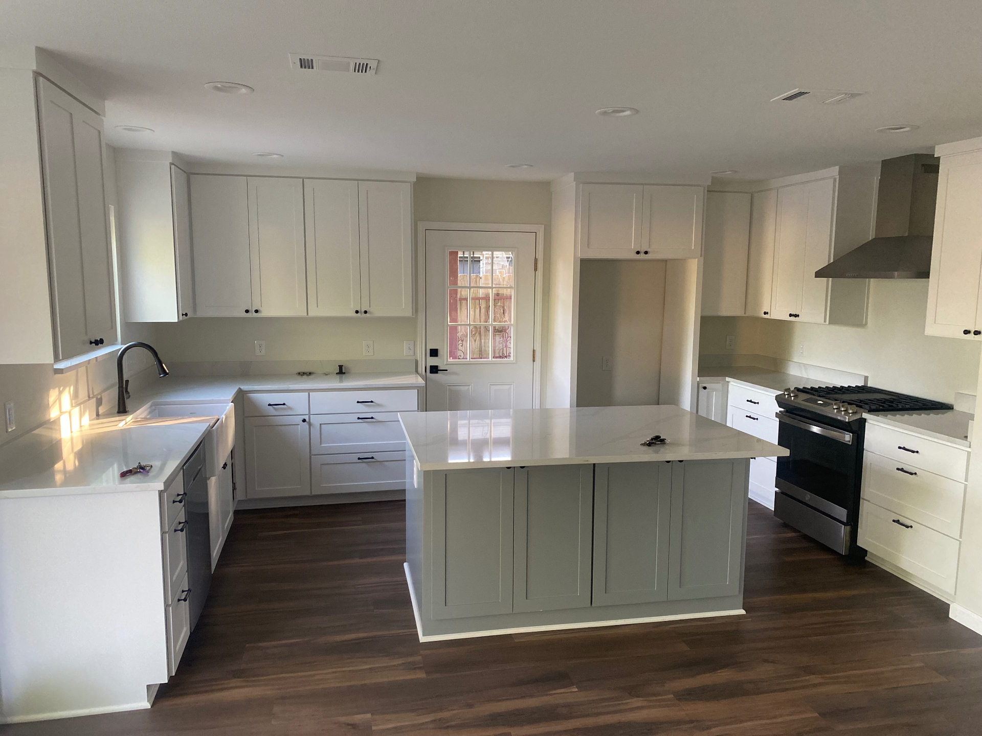 White shaker kitchen with a sage green painted island and quartz countertops