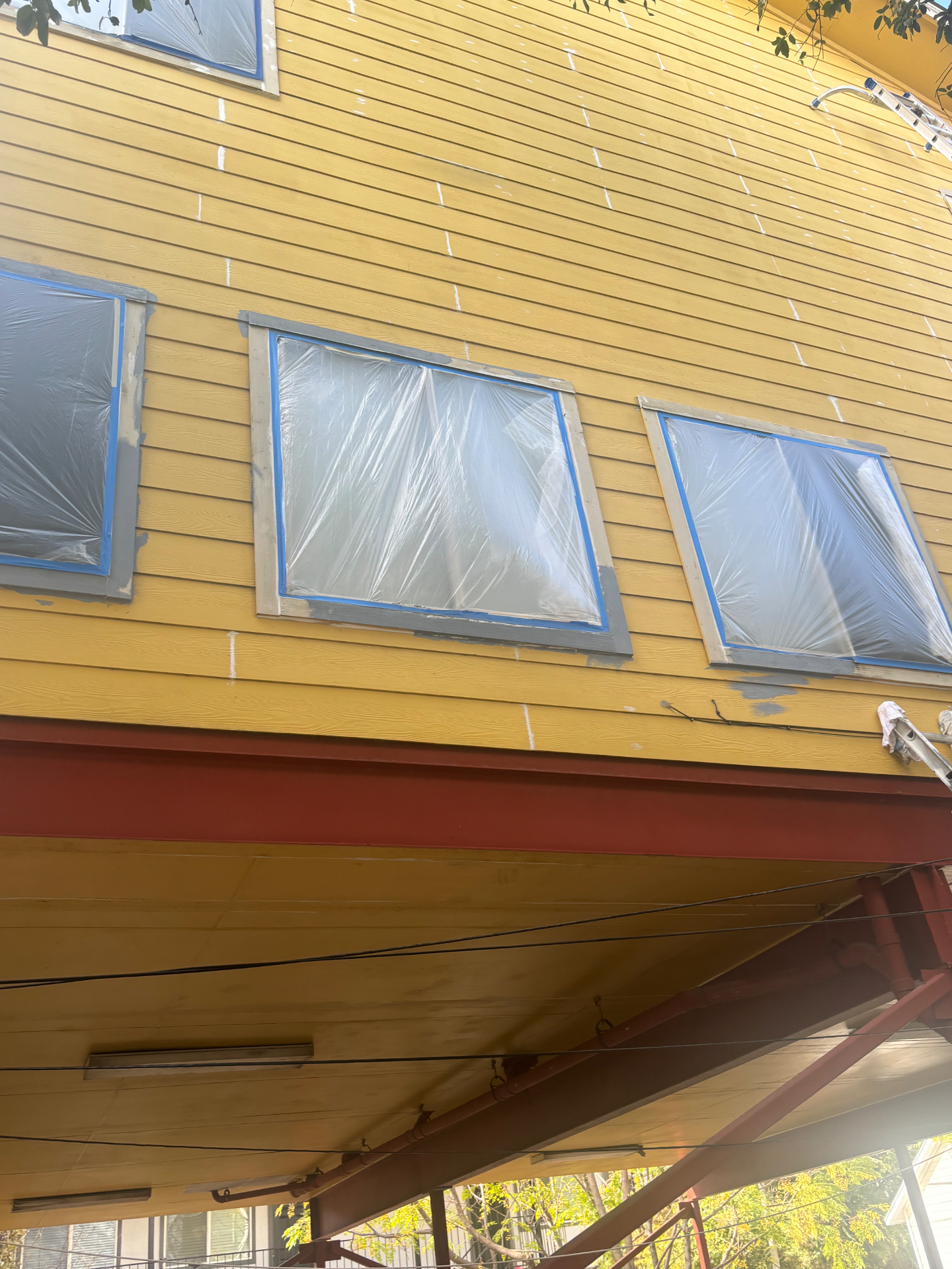 Exterior windows covered and siding repairs underway before painting
