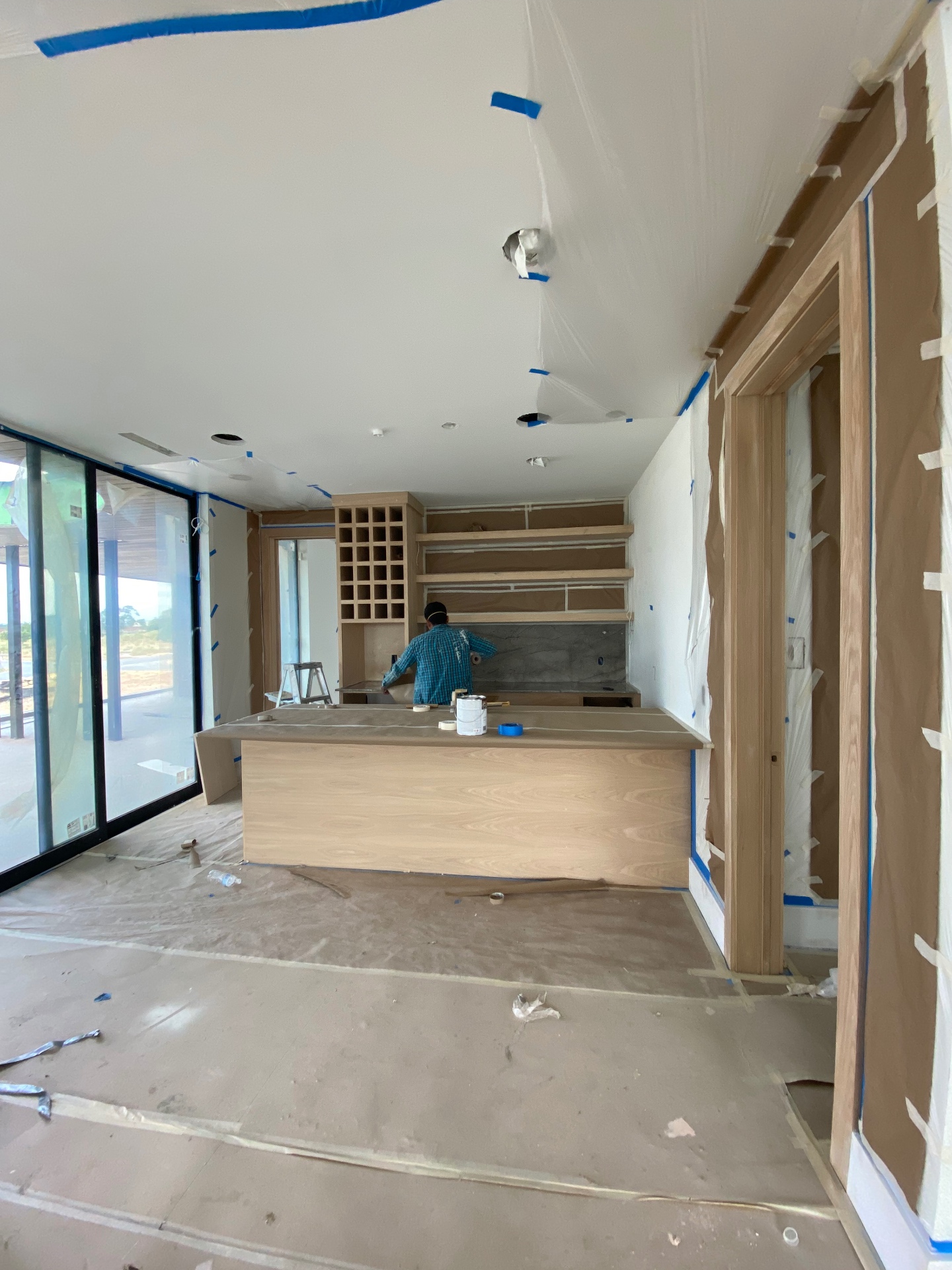 Kitchen cabinetry, ceiling, doors, and floors masked before a JJY Painting finish is applied