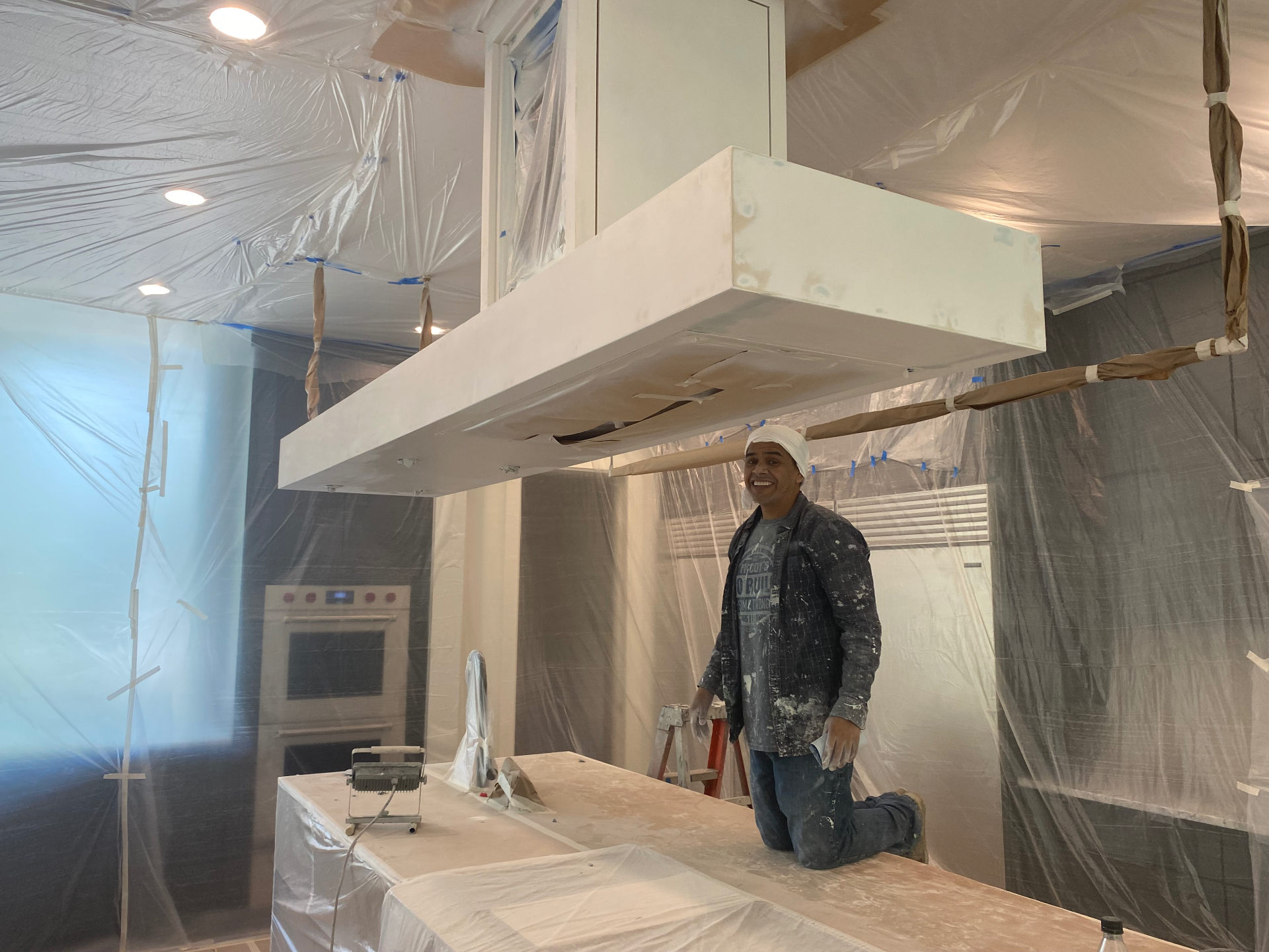 JJY Painting team member working inside a kitchen fully protected with plastic sheeting and masking