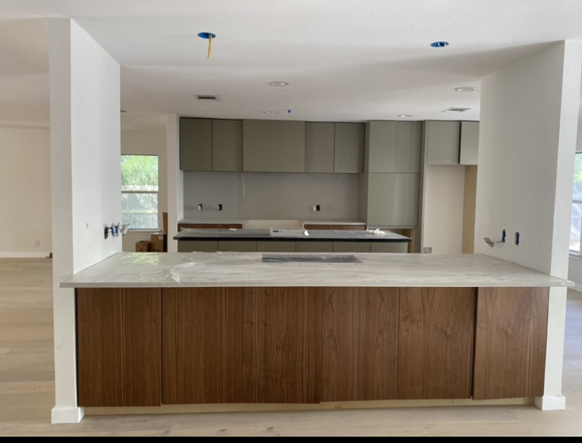 Modern kitchen with sage green upper cabinets and a walnut stained island